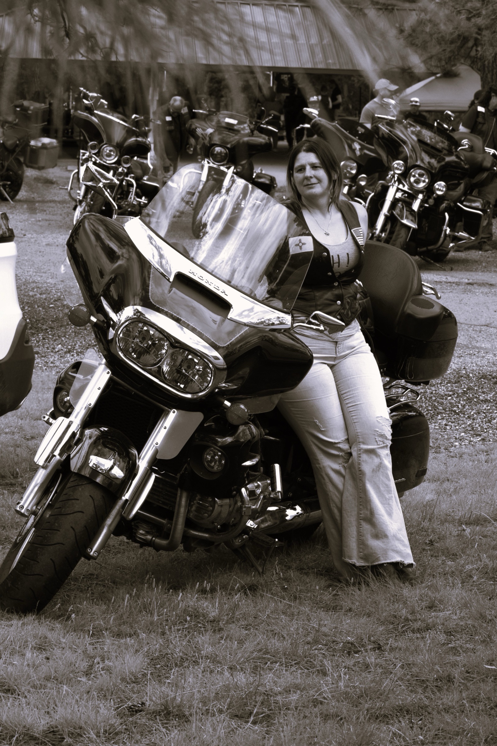 Black and white portrait of a woman leaning on a large touring motorcycle.