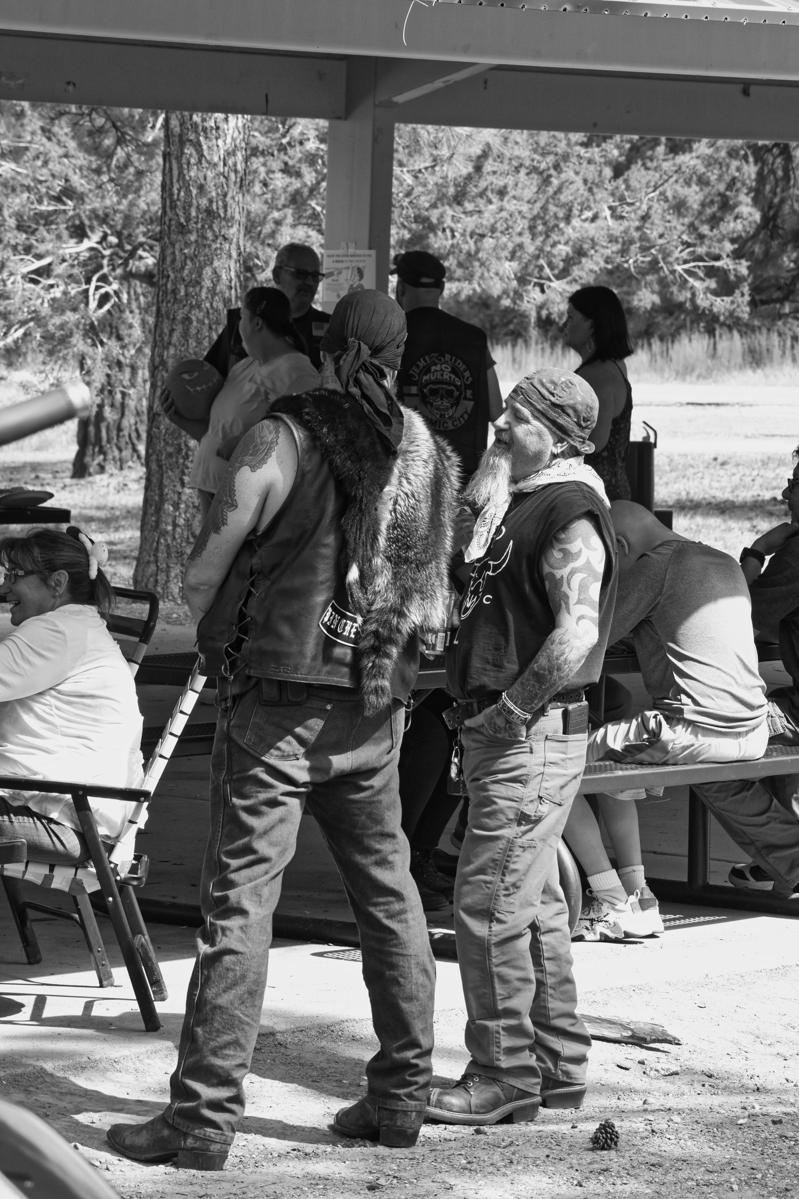 Black and white photo of a group of people talking under a shelter.